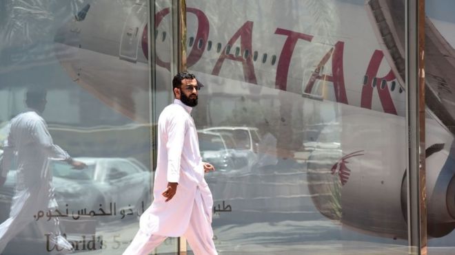 Человек на фоне эмблемы Катарских авиалиний