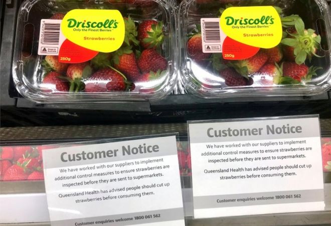 A customer notice near supermarket strawberries advises shoppers to cut them up before eating them