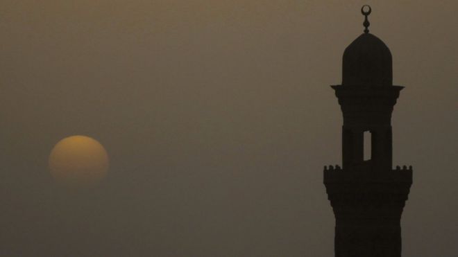 Минарет мечети изображен во время заката в туманный день в Каире, 8 апреля 2013 г.