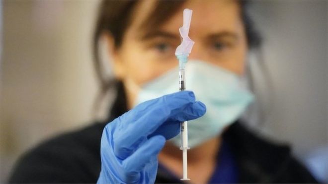 A woman holds a needle containing a covid vaccine