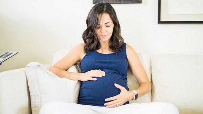 Беременная женщина, касаясь и глядя на ее живот