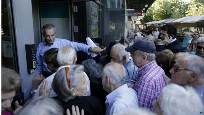 Менеджер банка открывает вход для пенсионеров в Афинах, среда, 1 июля 2015 г.