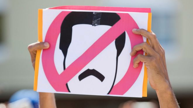 Венесуэльцы держат знак во время протеста, который венесуэльская община призывает против президента Мадуро
