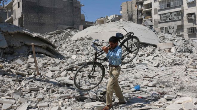 Syrian man carries bicycle through rubble of destroyed buildings following air strike on rebel-held Salihin neighbourhood of northern city of Aleppo, on September 11, 2016.
