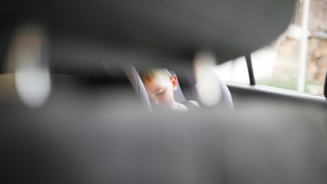 Foto tirada a partir de fronteira de carrro mostra criança dormindo na cadeirinha