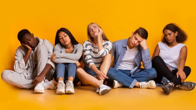 Cinco adultos jóvenes sentados en el suelo