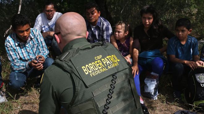 Агент пограничной службы США беседует с мигрантами из Центральной Америки, которые пытались въехать в США.