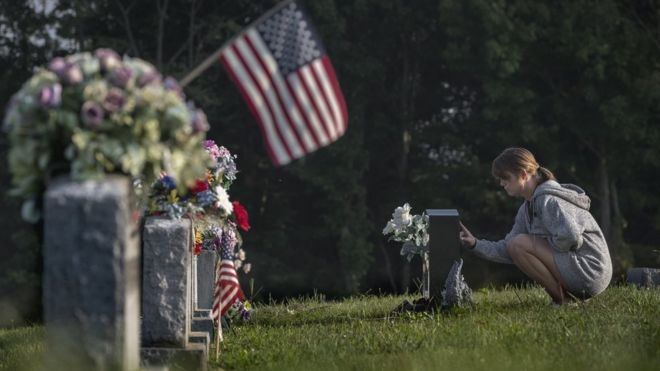 Женщина оплакивает могильный камень в Остине, штат Индиана