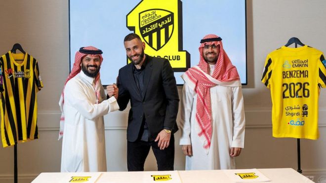كريم بنزيمة يقف مع أعضاء فريق الاتحاد السعودي لكرة القدم بعد توقيع عقده مع النادي