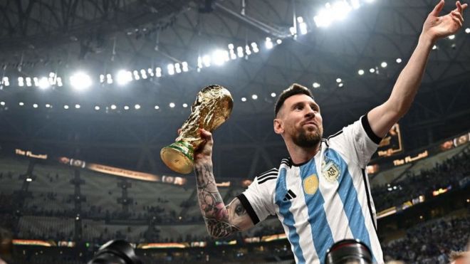 Messi is lifted by his team-mates, holding the World Cup