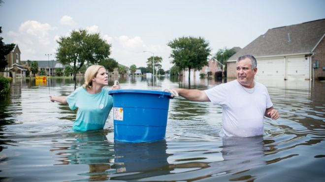 Дженна Фонтан и ее отец Кевин несут ведро с Ридженси Драйв, чтобы попытаться забрать предметы из их затопленного дома в Порт-Артуре, штат Техас, 1 сентября 2017 года