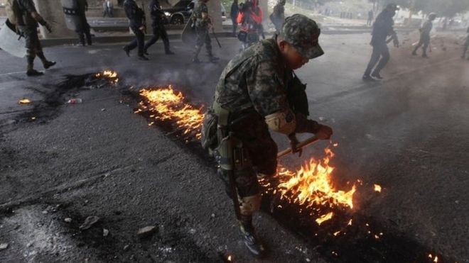 A soldier removes a burning tire set to block a road by opposition supporters during a protest over a disputed presidential election in Tegucigalpa, Honduras, December 11, 2017