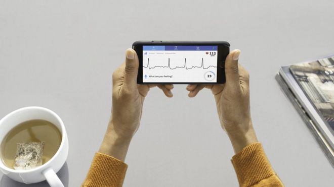 Женщина держит смартфон с диаграммой сердцебиения на экране