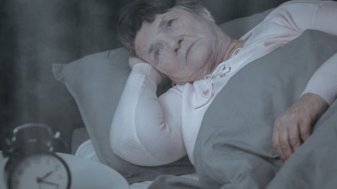 Пожилая женщина в постели страдает бессонницей