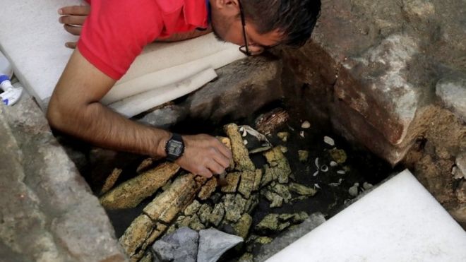 Археолог работает над 500-летним частично раскопанным каменным ящиком с ацтекской жертвой в Мехико, 25 марта 2019 года