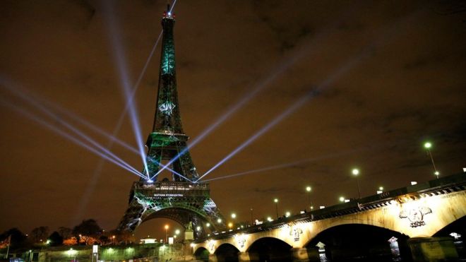 Накануне климатической конференции COP21 в Париже, Франция, 29 ноября 2015 года, Эйфелева башня озаряется цветами и надеждами.