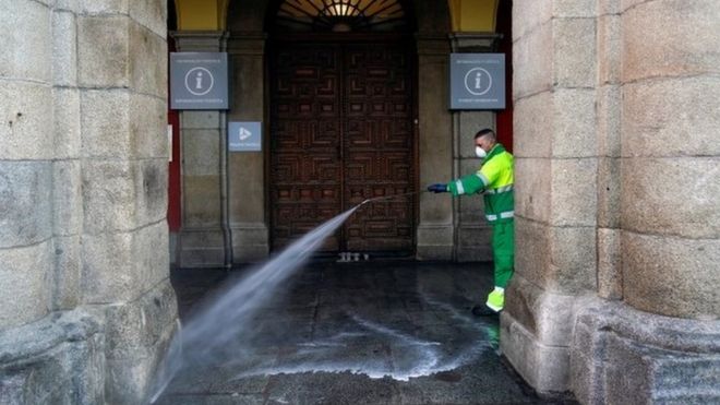 A worker at Madrid city hall hoses down a square