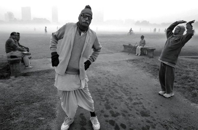 Мужчины поддерживают себя в форме ранним зимним утром в городском парке в Калькутте, Индия
