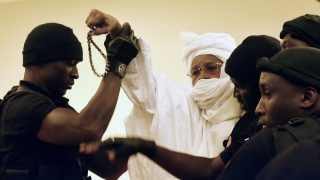 Бывший чадский диктатор Хиссин Хабре (С) сопровождается тюремными охранниками в зал суда для первого разбирательства по делу Чрезвычайных африканских палат в Дакаре 20 июля 2015 года.