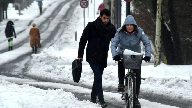Пешеход и велосипедист путешествуют по заснеженной улице в Монпелье, на юге Франции, 1 марта 2018 года