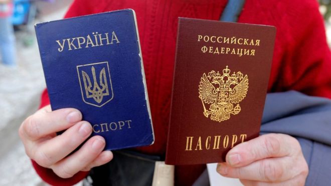 Женщина позирует с украинским паспортом (синий) и новым российским паспортом (красный) в Симферополе, Крым, 7 апреля 2014 года