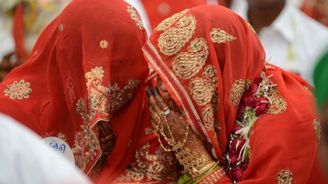 Muslim brides, veiled in red, speak during a mass wedding ceremony in 2015