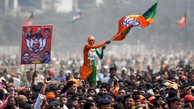 An Indian Bharatiya Janata Party (BJP) supporter waves a flag among the crowd of other supporters listening to Prime Minister Narendra Modi during the National Democratic Alliance (NDA) "Sankalp" rally in Patna in the Indian eastern state of Bihar on March 3, 2019