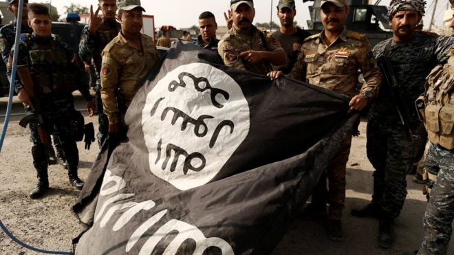Иракские солдаты позируют со знаменем Исламского государства в Шуре, к югу от Мосула, после взятия города (30 октября 2016 года)