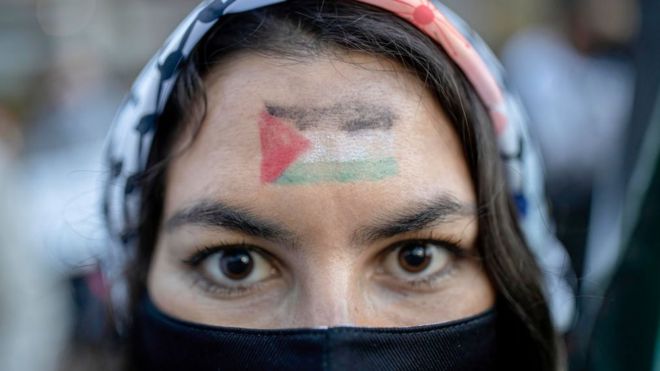 Mujer de origen palestino lleva la bandera de su país en la frente.