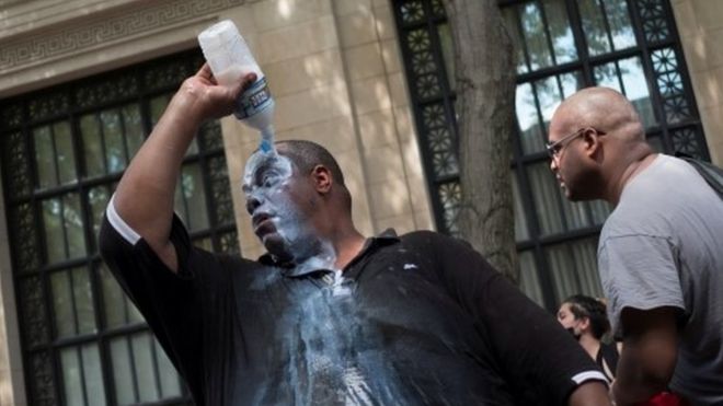 A man douses himself with a liquid, most likely milk of magnesium, to cope with the effects of pepper spray