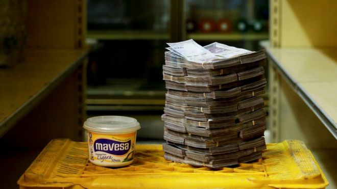 Чаша с маргарином изображена рядом со стопкой из 3 миллионов боливаров, что эквивалентно 46 центам США на рынке в Каракасе 16 августа