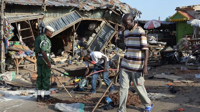 Мужчина проходит мимо места взрыва после того, как по меньшей мере 20 человек были убиты, когда молодая террористка-смертница взорвала ее взрывчатку на автобусной станции в Майдугури, северо-восточная Нигерия, 22 июня 2015 года в нападении, в котором, вероятно, обвиняют Боко. Хары.