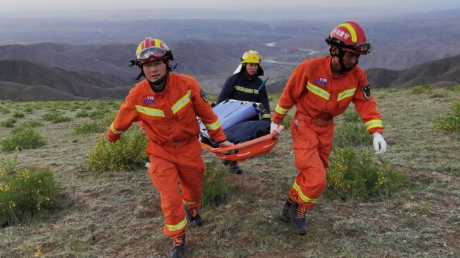 Rescuers carrying equipment as they search for runners who were competing in a 100-kilometre cross-country mountain race when extreme weather hit the area