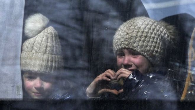 Una pequeña niña hace la forma de un corazón al ser evacuada de Mariúpol en marzo de 2022.