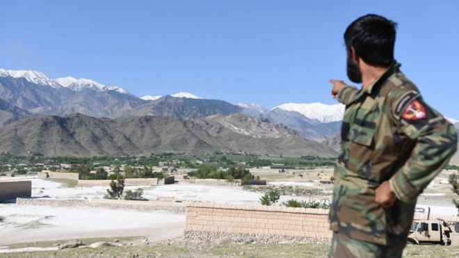 Афганский солдат указывает на район, где США сбросили бомбу