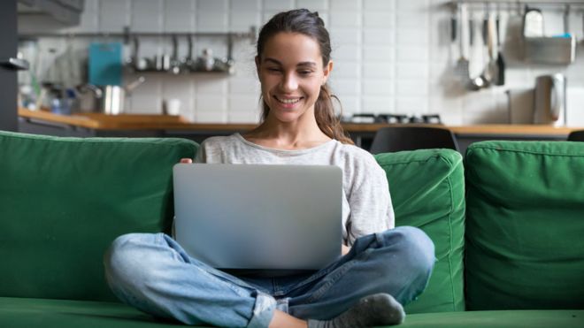 Una mujer mira sonriente su laptop