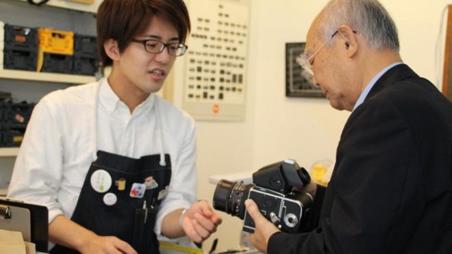 Un cliente de la tienda de Inada examina una vieja cámara.