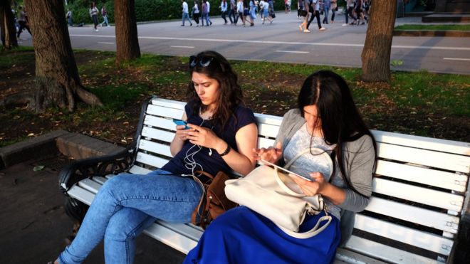 Девушки читают с планшентов в Парке Горького