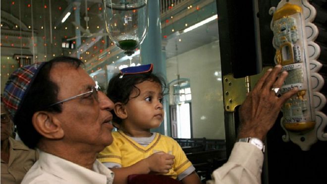 Индийский еврей с ребенком трогает мезузу в синагоге