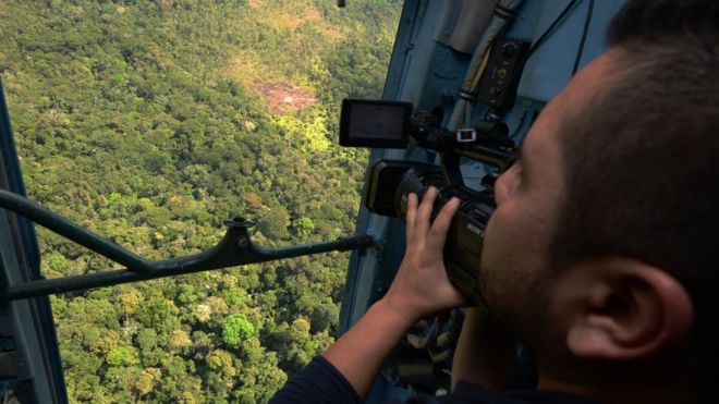 Homem observa selva a partir do helicóptero