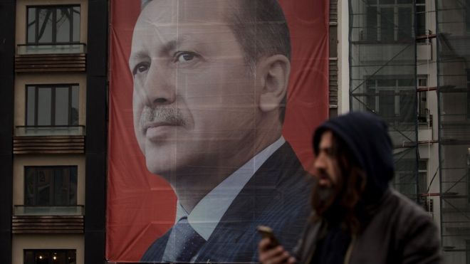 Люди проходят мимо большого баннера с портретом президента Турции Реджепа Тайипа Эрдогана на площади Таксим в Стамбуле, 13 марта