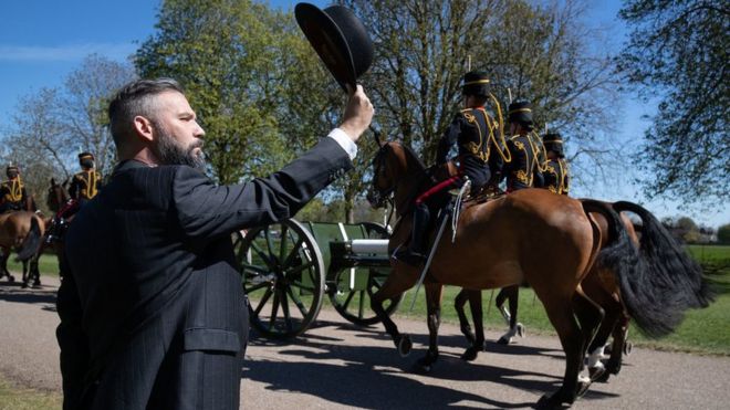 A person salutes the King's Troop Royal Horse Artillery as they make their way down the Long Walk towards Windsor Castle