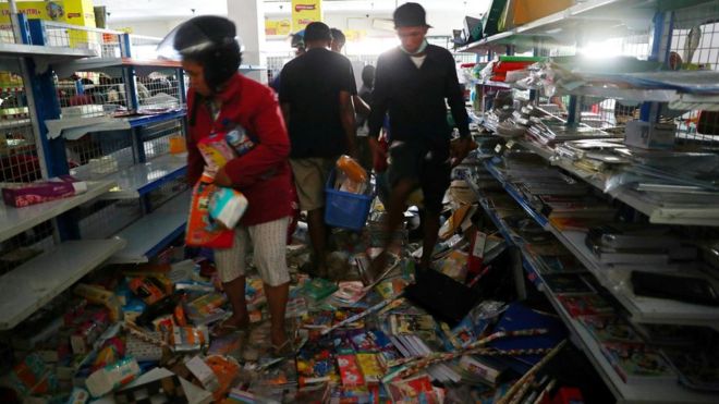 Earthquake and tsunami victims look for goods in a convenience store in Palu, Central Sulawesi, Indonesia, October 2, 2018