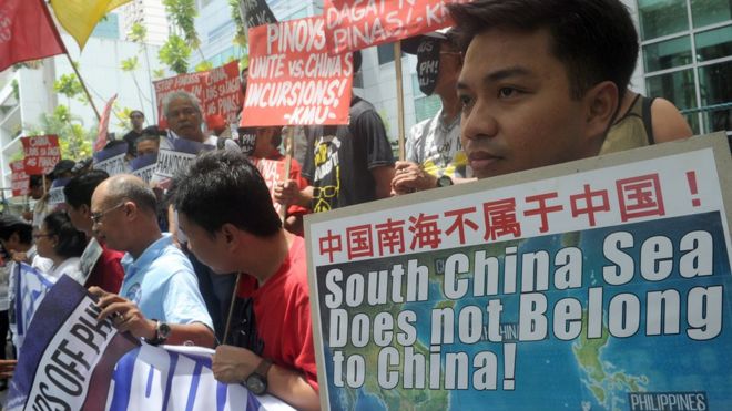Демонстранты с плакатами на митинге перед консульством Китая в финансовом районе Манилы, осуждая претензии Китая на большую часть Южно-Китайского моря