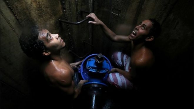 Местные жители собирают воду из подземного водопровода в Каракасе, Венесуэла, 12 марта 2019 года.