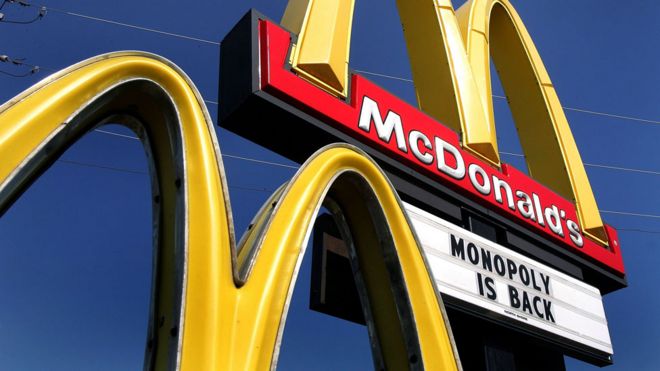 Los arcos dorados de McDonald's con un cartel promocionando el regreso del Monopoly.