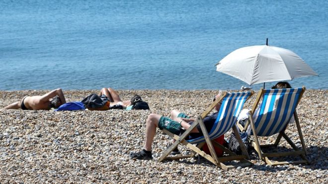 Люди наслаждаются теплой погодой на пляже в Брайтоне, Восточный Суссекс