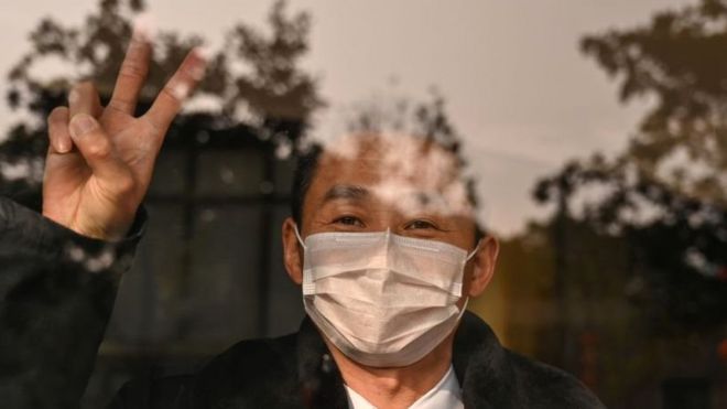 A hotel guard gestures while looking at the camera in Wuhan in China's central Hubei province