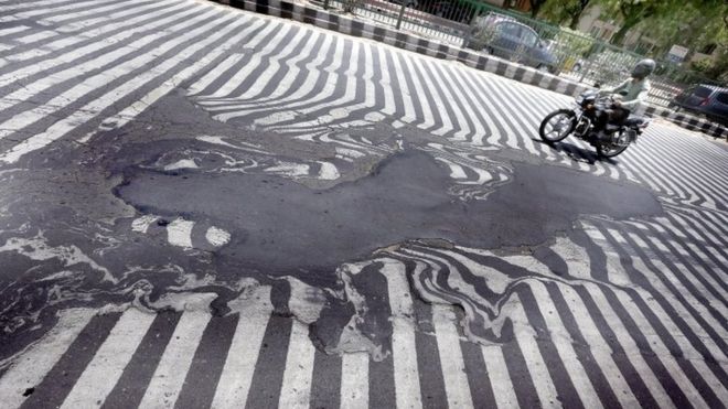 Мужчина из Индии едет на велосипеде по растаявшей дороге
