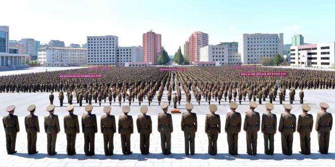 Hundreds of people in neat rank-ad-file gather in a main square in Pyongyang for an anti-US rally, facing a straight line of men in military uniform, who are apparently inspecting the rally
